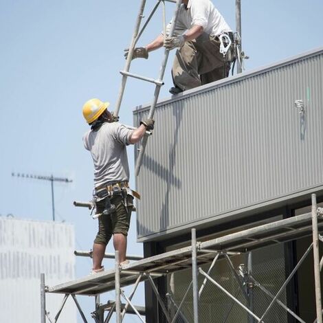 上から下に足場を運ぶスタッフ